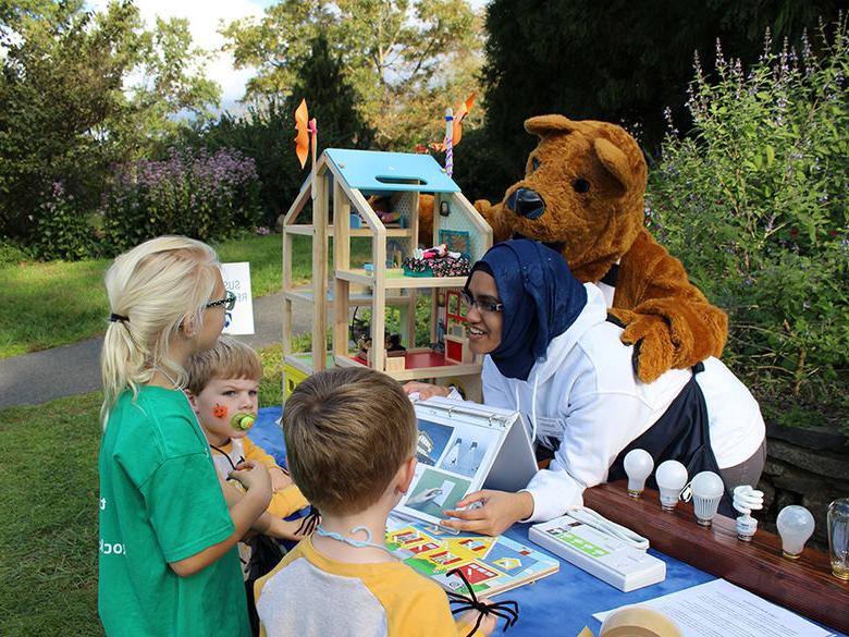 Student and lion mascot teaching children at community event.