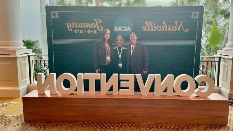 three women standing behind sign hat says Convention